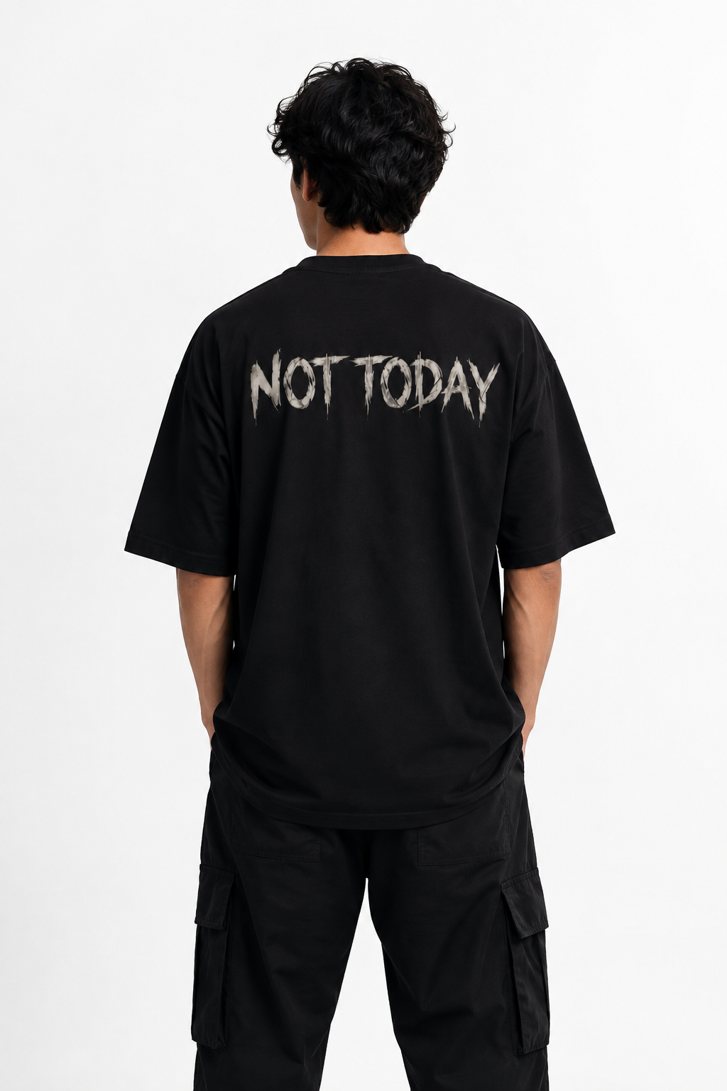 A man viewed from behind wearing a black t-shirt with 'NOT TODAY' printed in a distressed white font across the upper back, paired with black cargo pants against a plain white background.